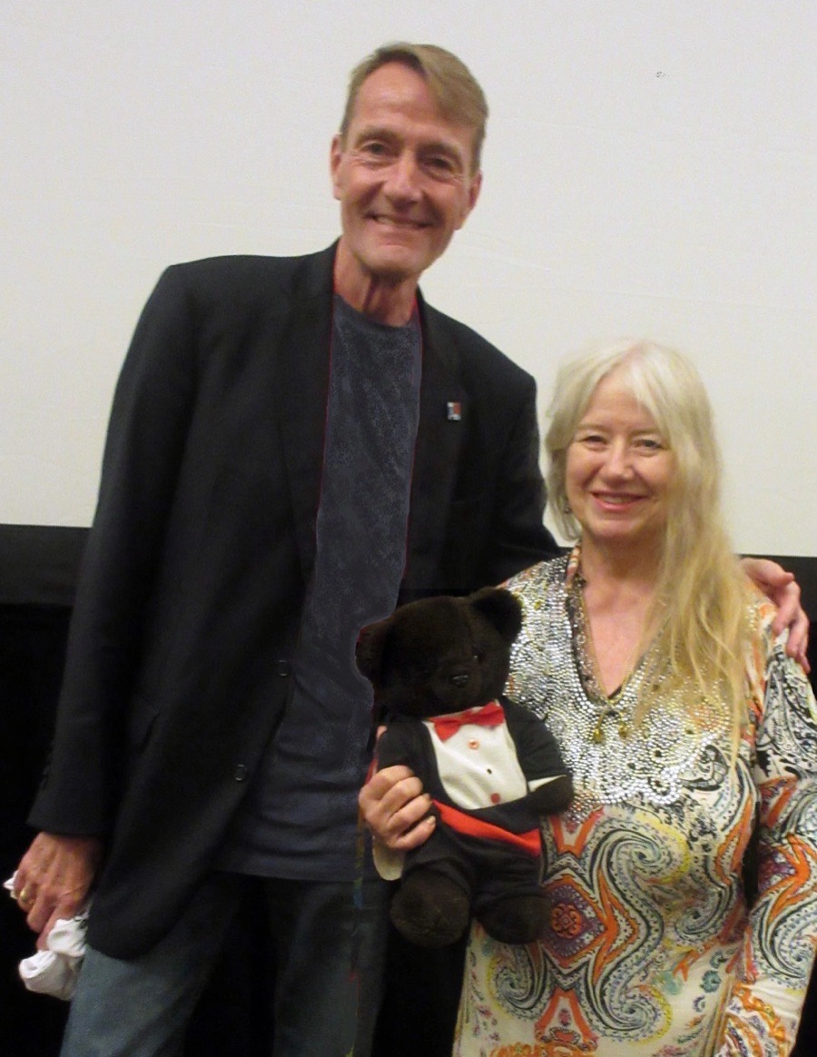 PatZi smiling with author Lee Child, holding her teddy bear Pekka in a tuxedo